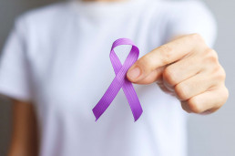 Hand holding purple Ribbon for Pancreatic, Esophageal, Testicula